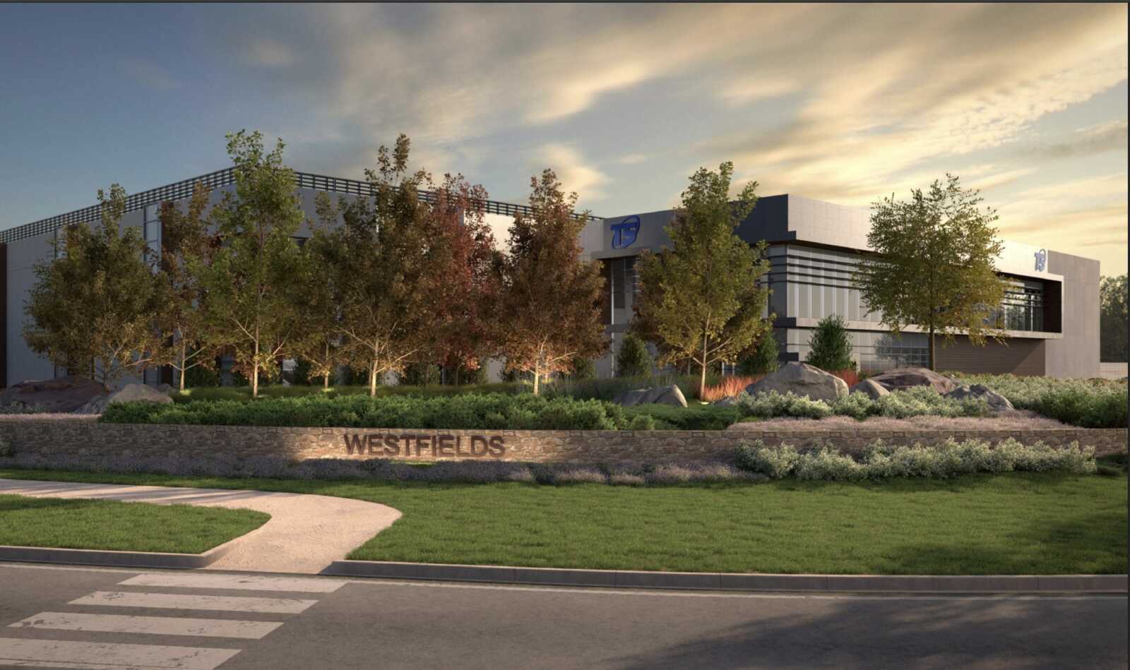 Modern office building named Westfields behind a landscaped stone wall and trees. sunset lighting.